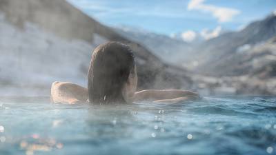 Frau im Außenpool mit Blick auf die Berge im Wellnessresort Amonti & Lunaris